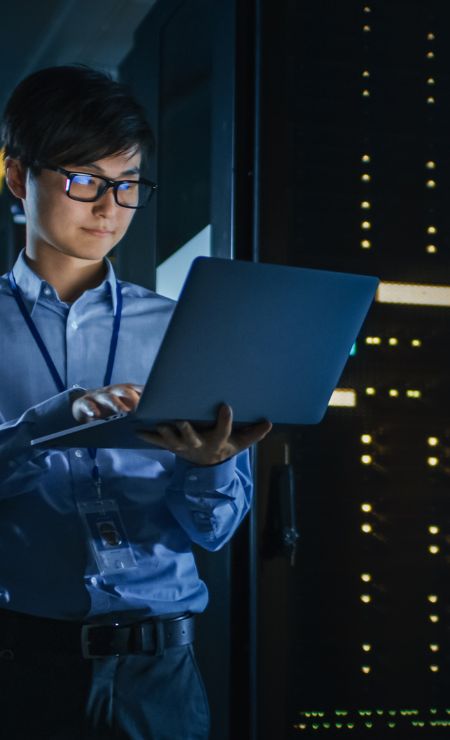 IT professional monitoring server room and laptop for cybersecurity solutions