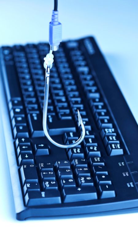 Keyboard with a fishing hook attached, symbolizing phishing attacks and cyber threats.