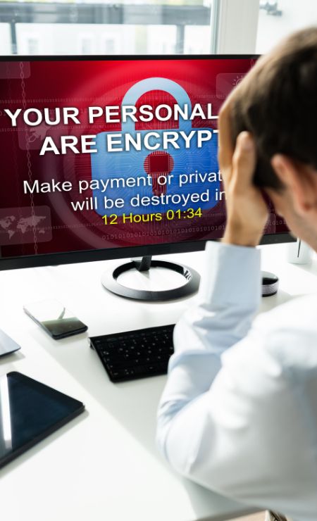 Person in front of computer displaying ransomware message about encrypted personal data, urging payment to avoid destruction, emphasizing urgency with countdown timer.