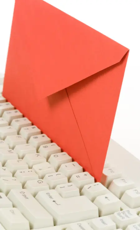 Red envelope resting on a white computer keyboard, symbolizing email communication and cybersecurity risks in business.