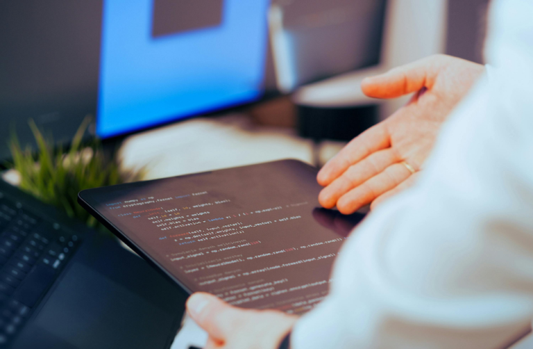 A person holding a tablet displaying lines of code. A managed IT expert responding to a potential cybersecurity threat.
